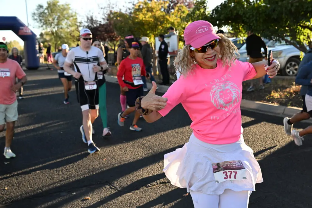 A runner throws her arms wide mid-course at the Santa Fe International Half Marathon